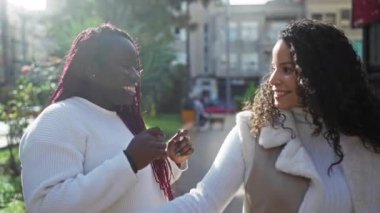 Kadın arkadaşlar şehir parkı ortamında konuşmaktan hoşlanırlar. Güneşli bir gün ışığında gülümser ve meşgul olurlar. Neşeli anları paylaşırlar..