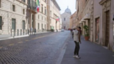Roma 'da bulanık binalar ve arka planda İtalyan mimarisini gözler önüne seren bokeh efektiyle odaksız caddede yürüyen bir adam..