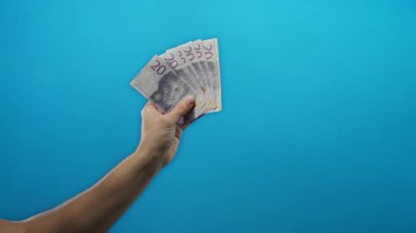 İsviçre banknotlarını elinde tutan adam, mali temalar ve İsveç 'i temsil eden para biriminin kullanımını tasvir eden, mavi izole bir arka plana karşı..