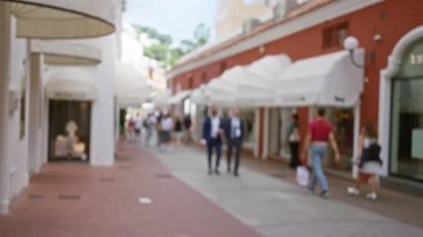Lüks Capri caddesinde yürüyen bulanık insanlar dükkanlar ve bokeh arka planlarıyla canlı bir atmosferi olan lüks bir ada ortamını işaret ediyor..