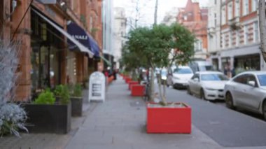 Bulanık şehir kış sokak sahnesi. Londra 'da dağılmış arabalar ve yayalar var. Bokeh' i ve sonbaharda tipik bir İngiliz caddesini gösteriyorlar..