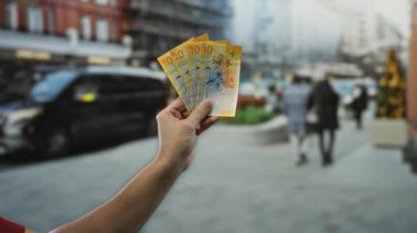 Elinde İsviçre frangı banknotları tutan bir adam şehrin caddelerini insanlarla ve arabalarla görüntülüyor..