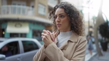 Şehirli bir caddede kendine güvenen bir kadın, elleri sımsıkı bağlı, hareketli bir şehir ortamında güzelliğini ve tarzını sergiliyor..