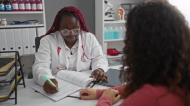 Doktor ve hasta bir klinikte muayene ediyorlar. Tıbbi kayıtlar masanın üzerinde. Hastane ortamında sağlık hizmetleri etkileşimi gösteriliyor..