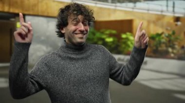 Kentsel sokak ortamında gülümseyen ve coşkuyla dans eden genç bir adam. Günlük kıyafet ve neşeli ifadeyle pozitifliği vurguluyor..