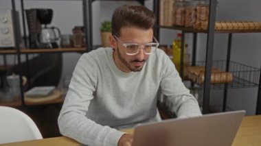 Gözlüklü genç adam. Ofis ortamında gözleri ovuşturuyor. Arka planda raflar var..