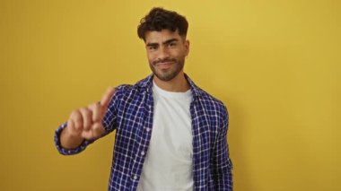 Sakallı genç adam parmakları parlak sarı arka planda değil, hoşnutsuzluk ya da inkarı ifade ediyor..