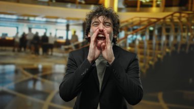 Genç İspanyol adam modern otel resepsiyonunda şık bir iç tasarımla bağırıyor. Bulanık arka planda canlı bir atmosfer yaratıyor..