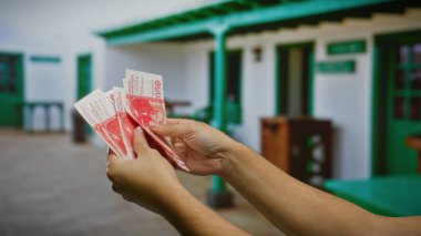 Açık havada elinde kırmızı banknotlar tutan bir adam, şehir tatil ortamında, muhtemelen İzlanda Krona para birimi ile seyahat, yatırım veya finansal takas öneriyor..