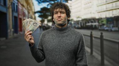 İngiliz banknotlarını elinde tutan İspanyol bir adam şehir sokağında İngiltere 'nin parasını dışarıda sergiliyor..