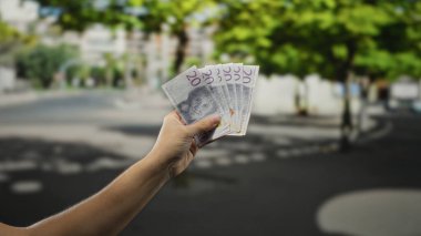 Bir şehir caddesinde elinde İsveç kronu banknotları tutan bir adam paranın ve şehir hayatının özünü yakalıyor..
