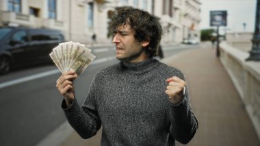 Şehir sokaklarında Rus rublesi tutan İspanyol bir adam, halka açık bir şehir ortamında heyecan ve başarı sergiliyor..