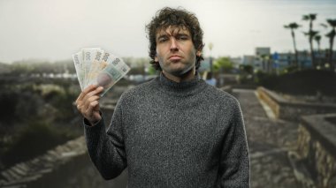 Elinde Czech Koruna banknotları olan bir adam şehir sokaklarında, elinde para olan İspanyol bir erkeği sergiliyor, şehir atmosferini yakalıyor..