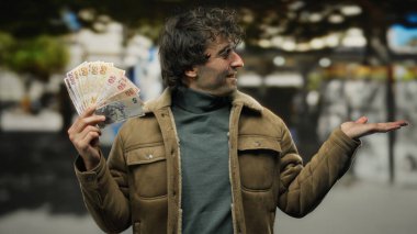 Bir şehir caddesinde İspanyol bir adam elini uzatıyor, Türk lira banknotlarını tutuyor, canlı bir para ve fırsat manzarası yaratıyor..