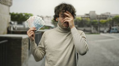 Şehrin dışındaki İspanyol adam Polonya 'da finansal konseptleri gösteren zloti banknotları tutuyor..