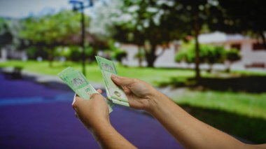 Açık şehir ortamında Malezya halkalarını tutan eller, şehir parkının arka planında para transferlerini sergiliyorlar..