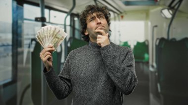 Otobüsteki İspanyol adam elinde Rus rublesi tutarken otobüste kafa yoruyor. Toplu taşıma araçlarında mali tefekkür sahnesi yaratıyor..
