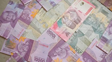 Endonezya rupia banknotları çeşitli mezhepleri ve renkleri gösteren düz bir yüzeye saçılmış.