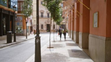 Bulanık yayalar, yüksek binalar ve turuncu cepheleriyle Avrupa 'nın pitoresk caddelerinde yürüyor ve dağılmış bir sahnede sıcak bir şehir ortamı yaratıyor..