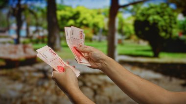 Kentsel park ortamında Tayvan doları tutan, açık hava ortamında iş ve yatırım amaçlı para birimi sayısını gösteren bir adam..