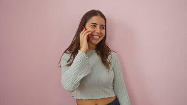 Pembe arka planda telefonla konuşan gülümseyen kadın sıcaklığı ve modern bağlantıyı gösteriyor.