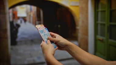 Bir şehir caddesinde Meksika pezosu tutan bir adam, renkli banknotlar ile bir iş alışverişini vurguluyor açık şehir ortamında, yatırım fırsatlarını vurguluyor.