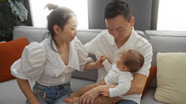 Anne-baba ve erkek çocuk sıcak bir oturma odasında birlikte oturuyorlar. Evlerinde sevgi dolu bir aile anı yaratıyorlar..