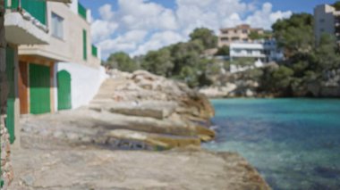 Santanyi, Mallorca 'da bulanık evler ve turkuaz suların rüya gibi bir bokeh etkisi yarattığı pitoresk bir Akdeniz sahili..