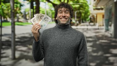 Bir şehir sokaklarında İngiliz banknotlarını elinde tutarken gülümseyen İspanyol bir adam, şehir manzarası, sergilenen finansal başarı ve neşeli bir tavır..