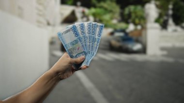 Macar banknotları elinde tutan adam hareketli bir şehir sokaklarında para gösteriyor. Canlı bir şehir sahnesinde, seyahat ve finans konuları için mükemmel..