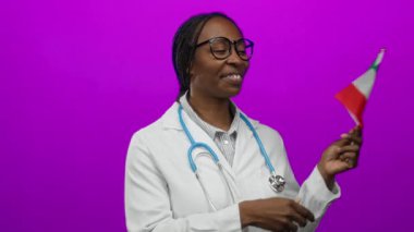 Gülümseyen kadın doktor, canlı pembe arka plana karşı steteskoplu İtalyan bayrağı tutuyor ve çok kültürlü sağlık temalarını vurguluyor..