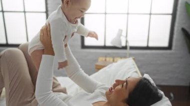 Yatak odasında kızıyla oynayan bir kadın. Sıcak bir evin içinde sevgi ve neşe dolu.