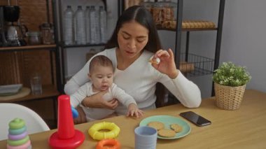 Anne ve bebek evde oyuncaklarla ve atıştırmalıklarla güzel vakit geçiriyorlar. Konforlu bir ev mutfağında aile bağı kuruyorlar..