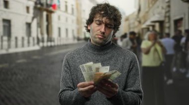 Kalabalık bir şehir caddesinde Czech Koruna 'yı açık havada tutan adam şehir geçmişinde odaklanma ve konsantrasyon gösteriyor..