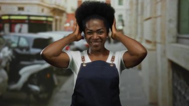 Şehir caddesinde gülen önlük giymiş bir kadın. Etrafı bulanık araba ve binalarla çevrili. Gündüz vakti şehir merkezinde..