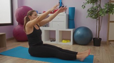 Spor salonunda paspas üzerinde egzersiz yapan bir kadın sağlık odaklı bir ortamda bitki ve ekipman gösterme uygunluğu ve esnekliği gösteriyor..