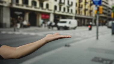 Şehir sokaklarındaki adam, trafik ve yayaların yoğun olduğu şehir ortamında onay vermek için avucunun içini işaret ediyor..