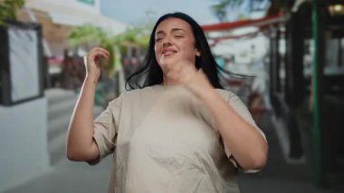 Kentsel sokak ortamında güven içinde gülümseyen bir kadın açık hava ortamında iyimserlik ve kendine güvenin olduğunu gösteriyor..