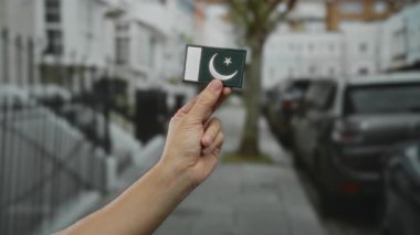 Canlı bir şehir caddesinde elinde Pakistan bayrağı olan bir adamın eli..