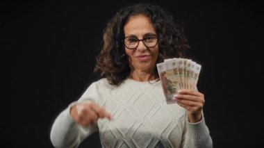 Elinde Rus rublesi olan kadını işaret ederek para ve finans kavramlarını vurgulayarak zenginlik ve tasarrufları resmetmeye çalışıyor.