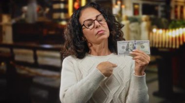 Kilisedeki kadın, Amerikan dolarlarını tutan, para ve maneviyatla ilgili duygularını kapalı bir ortamda aktaran..