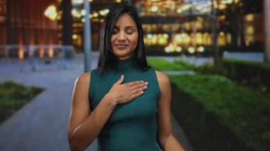 Gece şehir caddesinde yeşil bluz giyen, bağlılık, söz ve samimiyeti temsil eden, arka planda bulanık ışıklarla yemin eden bir kadın..