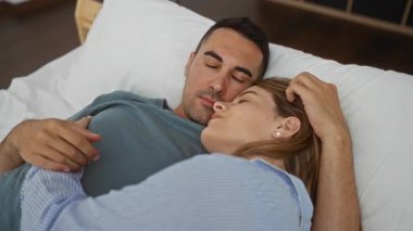 Çift yatakta dinleniyor, kadın ve erkek barışçıl bir şekilde kucaklaşıyor, kapalı bir ortamda sevgi ve rahatlık gösteriyor, modern bir yatak odasında sıcaklık uyandırıyor..