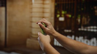 Arka planda tarihi binalar bulunan şehir sokağında İsrail Şekel banknotlarını inceleyen adam, açık havada mali kararlar verildiğini gösteriyor..