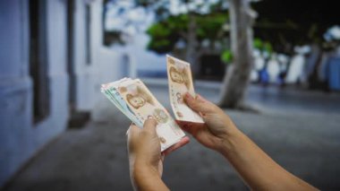 Bir şehir caddesinde Çin Yuan banknotları tutan eller, para ve iş işlemlerini gösteren şehir ortamında.