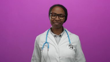 Steteskoplu kendine güvenen kadın doktor canlı pembe arka plana karşı zafer için kollarını kaldırıyor..