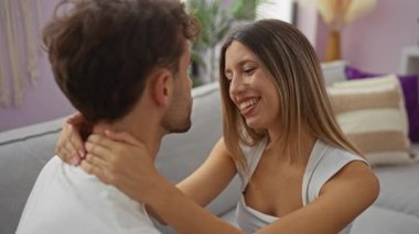 Evdeki kanepeye yakın oturan çift, sıcak bir oturma odasında birlikte mutlu ve sevgi dolu bir anı paylaşıyor, ilişkilerinin güzelliğini yakalıyorlar..