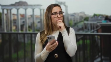 Roma 'daki Roma harabelerinin yanında akıllı telefonlu bir kadın, tarihi mimari ve manzaralı manzaralarla çevrili, antik kültür ve modern teknolojinin bir karışımını sergiliyor..