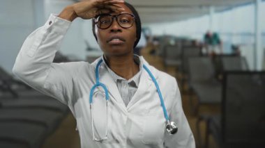 Güvertede steteskobu olan doktor kadın, açık deniz ortamında profesyonellik ve özen göstererek, gülümseyip işaret ederken dikkatlice denize bakıyor..