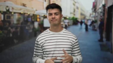 Şehrin hareketli bir caddesindeki terasta duran adam rahat bir restoranın önünde açık şehir ortamında rahat ve kendinden emin bir hava yayıyor..